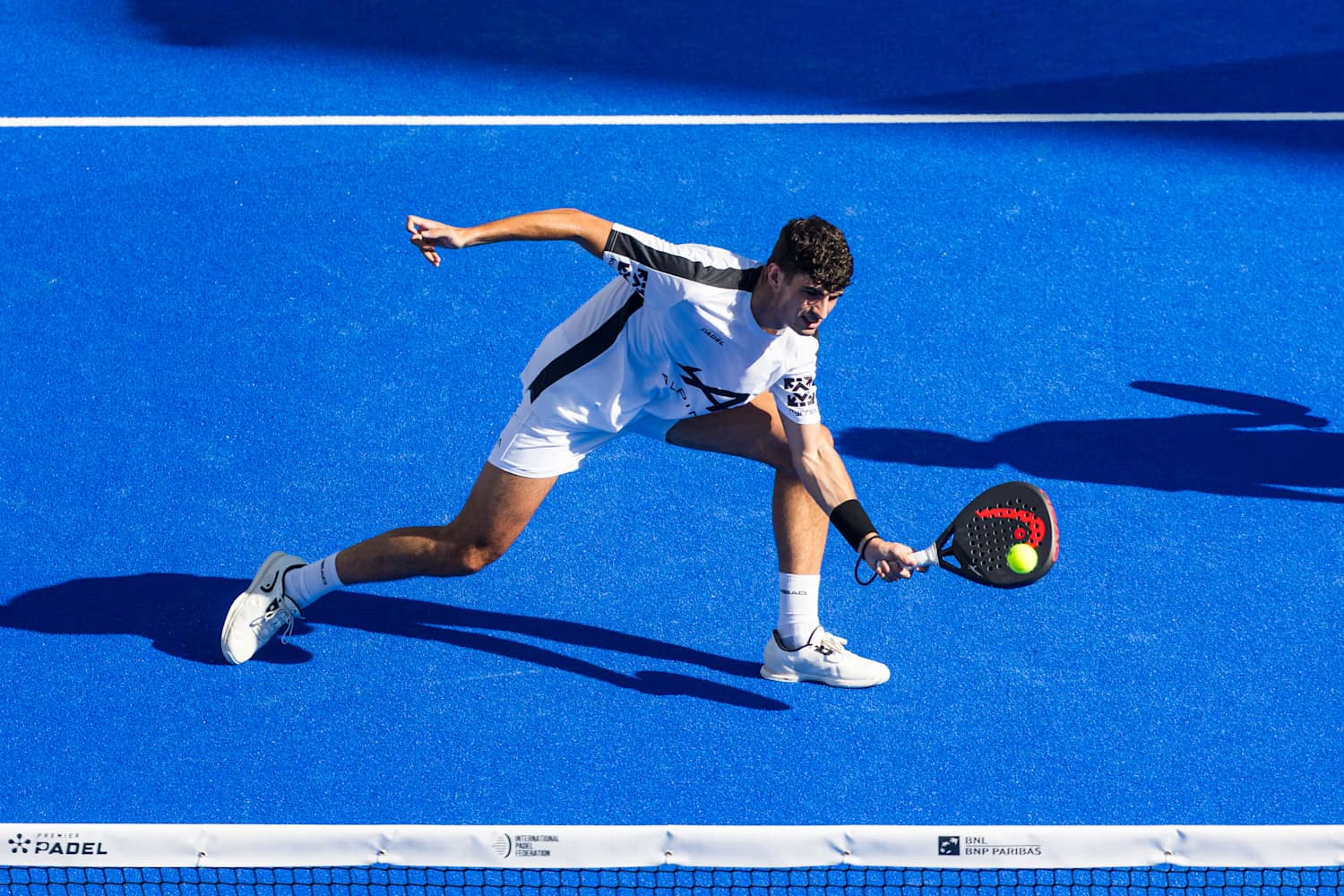 Jugadora de pádel con raqueta en cancha con paredes de cristal