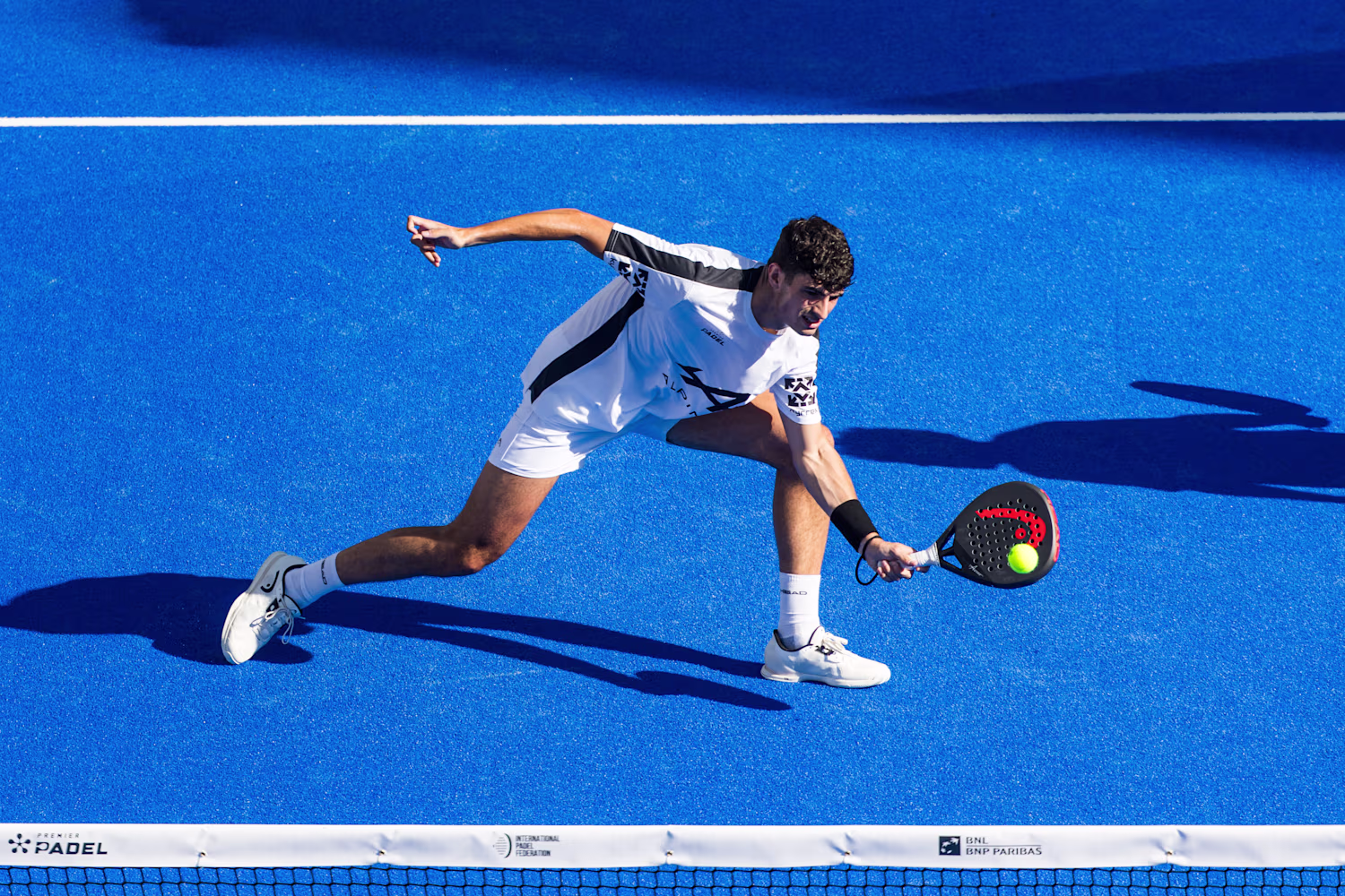 Jugadora de pádel con raqueta en cancha con paredes de cristal